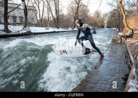 Surfer fahren stromaufwärts im Eisbach in München. Stockfoto