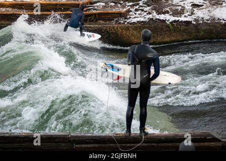 Surfer fahren stromaufwärts im Eisbach in München. Stockfoto