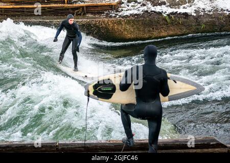 Surfer fahren stromaufwärts im Eisbach in München. Stockfoto