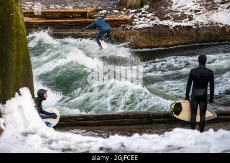 Surfer fahren stromaufwärts im Eisbach in München. Stockfoto