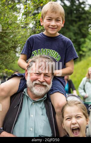 Seattle, Washington, USA. Der siebenjährige Junge, der von seinem Großvater eine Huckepack-Fahrt gemacht hat, und seine neunjährige Schwester, die ebenfalls Spaß hat, hat sich auf den Weg gemacht. (M Stockfoto