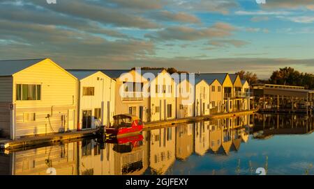 USA, Washington State, Kennewick. Das rote Boot spiegelt sich im Abendlicht auf der Clover Island Marina entlang des Columbia River wider. Stockfoto