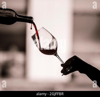 USA, Washington State, Woodinville. Rotwein, der in das Glas fließt, mit Weintropfen, der mitten in der Luft eingefangen wird. Stockfoto