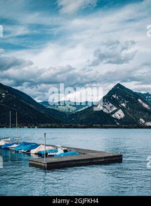 Steg mit kleinen Booten, die im See an den Bergen festgemacht sind Stockfoto