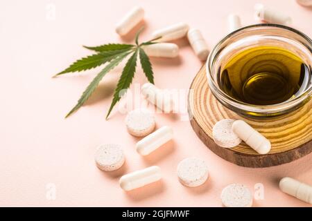 CBD-Öl in Glasflaschen und Cannabisblätter am weißen Tisch. Stockfoto