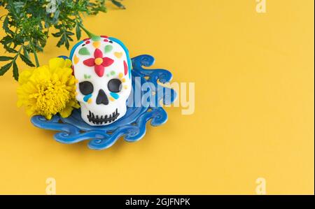 Tag der Toten. Totenkopf auf blauem Teller mit Farben auf gelbem Hintergrund. Speicherplatz kopieren. Mexikanische Party. Stockfoto