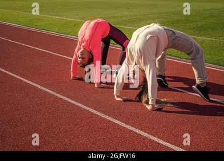 Flexible Mädchen Turnerinnen stehen in Krabbenposition auf der Leichtathletik-Strecke, Flexibilität. Stockfoto