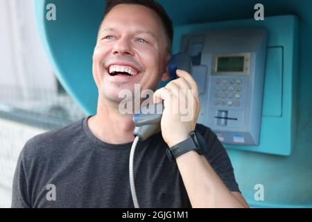 Fröhlicher, lächelnder junger Mann, der am Stand telefoniert Stockfoto
