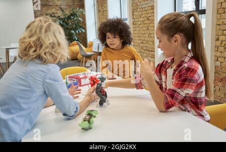 Verschiedene Kinder untersuchen, betrachten technische Spielzeuge auf dem Tisch voller Details während der Engineering-Klasse Stockfoto