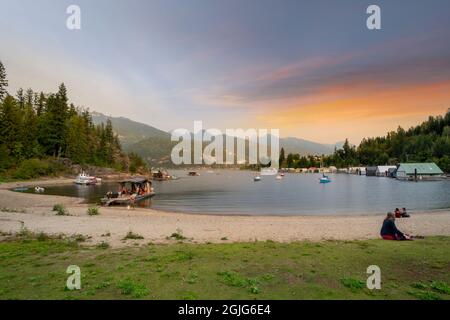 Die Einheimischen genießen den Sonnenuntergang am kleinen Strand, der Werft und dem Park als Kaslo Bay, in dem kleinen Dorf Kaslo, BC, Kanada. Stockfoto