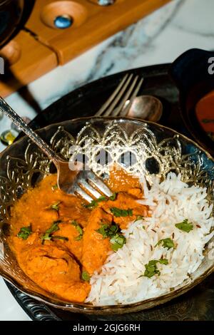 Spielen von Mancala Brettspiel beim Essen von indischem Essen einschließlich Huhn Tikka und pindi Chana Masala sowie Aloo Matar Stockfoto