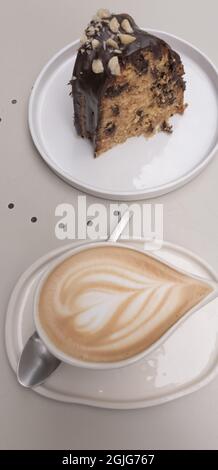 Kaffee mit Milch, begleitet von einem Stück Schokoladenkuchen Stockfoto