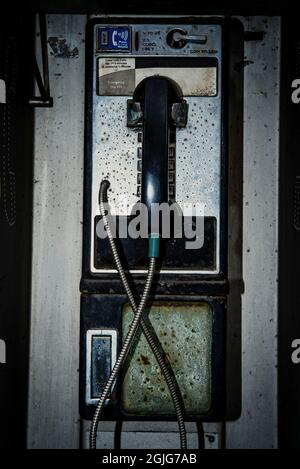 Altes, dreckiges, altes Münztelefon auf der Straße, das mit Abgasen und Schutt bedeckt war Stockfoto