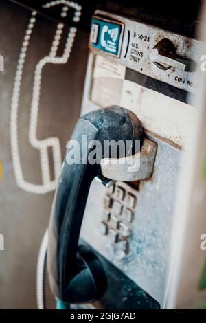 Altes, dreckiges, altes Münztelefon auf der Straße, das mit Abgasen und Schutt bedeckt war Stockfoto