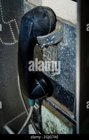 Altes, dreckiges, altes Münztelefon auf der Straße, das mit Abgasen und Schutt bedeckt war Stockfoto