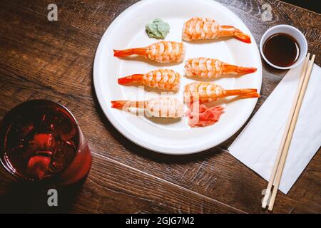 Japanisches Shrimp-Nigiri-Sushi mit Wasabi und eingelegtem Ingwer in dunkler, modischer Beleuchtung Stockfoto
