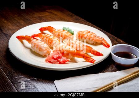 Japanisches Shrimp-Nigiri-Sushi mit Wasabi und eingelegtem Ingwer in dunkler, modischer Beleuchtung Stockfoto