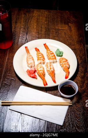 Japanisches Shrimp-Nigiri-Sushi mit Wasabi und eingelegtem Ingwer in dunkler, modischer Beleuchtung Stockfoto