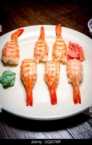 Japanisches Shrimp-Nigiri-Sushi mit Wasabi und eingelegtem Ingwer in dunkler, modischer Beleuchtung Stockfoto