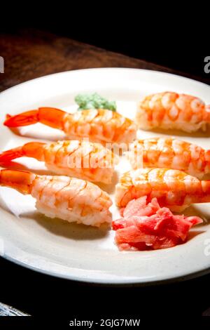 Japanisches Shrimp-Nigiri-Sushi mit Wasabi und eingelegtem Ingwer in dunkler, modischer Beleuchtung Stockfoto