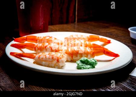 Japanisches Shrimp-Nigiri-Sushi mit Wasabi und eingelegtem Ingwer in dunkler, modischer Beleuchtung Stockfoto
