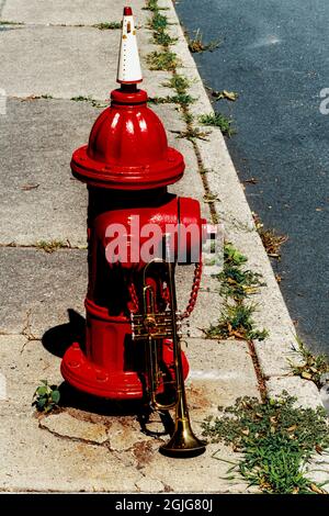 Summer Jazz Instrument Trompete steht allein gegen roten Feuerhydranten auf der Stadtstraße Stockfoto