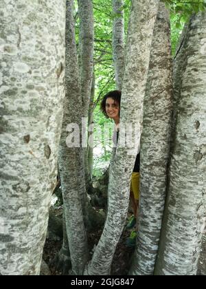 Italienische Frau, die sich im Wald des Passo San Leonardo, Pacentro, Italien, an Bäumen lehnt Stockfoto