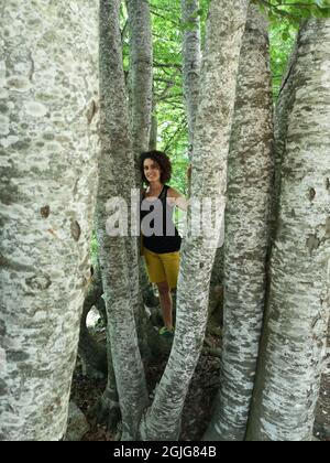 Italienische Frau, die sich im Wald des Passo San Leonardo, Pacentro, Italien, an Bäumen lehnt Stockfoto