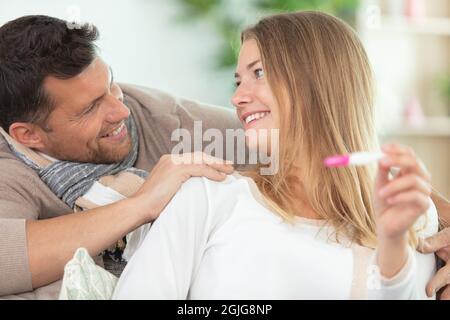Glückliches Paar überprüft Schwangerschaftstest sitzen auf einer Couch Stockfoto