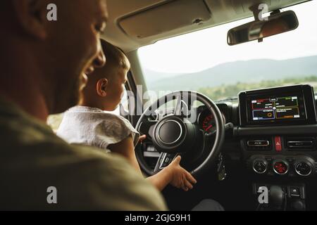 Vater lehrt den kleinen Sohn auf einer Autoreise zu fahren Stockfoto