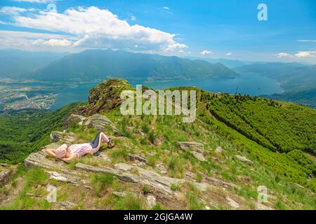 Frau, die sich auf dem Cardada-Cimetta-Berg in der Schweiz entspannt. Skyline von der Schweizer Seilbahn von Locarno auf dem Cardada-Berg. Langensee Stadtbild in Stockfoto