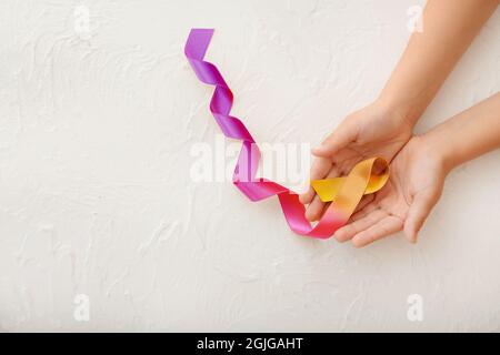 Hände mit buntem Band auf weißem Hintergrund. Konzept zur Sensibilisierung für Blasenkrebs Stockfoto