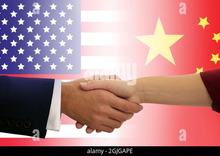 Menschen schütteln die Hände gegen die Flaggen der USA und Chinas Stockfoto