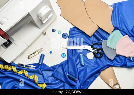 Nähmaschine mit Schneiderzubehör und Schutzmasken auf hellem Hintergrund Stockfoto