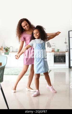 Afroamerikanische Frau mit ihrer kleinen Tochter, die in der Küche tanzt Stockfoto