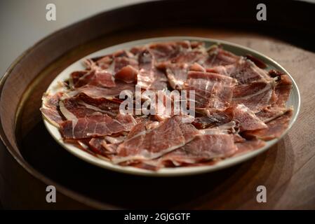 Platte mit geschnittenem Schinken auf einem Weinstiefel Stockfoto