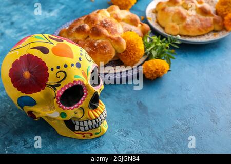 Bemalter Schädel und Brot der Toten auf farbigem Hintergrund. Feier des mexikanischen Tages der Toten (El Dia de Muertos) Stockfoto