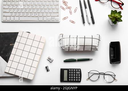 Komposition mit Schreibwaren, Tastatur und Etui auf weißem Hintergrund, Nahaufnahme Stockfoto