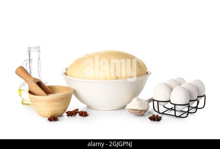 Schüssel mit frischem Teig, trockener Hefe und Zutaten auf weißem Hintergrund Stockfoto