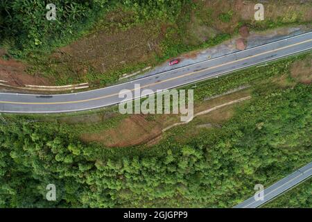 Reisen Sie auf hügeliger Straße im Frühjahr Luftaufnahme Straßenkurvenkonstruktion bis zum Berg erstaunlich von oben nach unten Bild von Drohne Kamera. Stockfoto