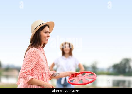 Schöne junge Frauen spielen Frisbee im Freien Stockfoto