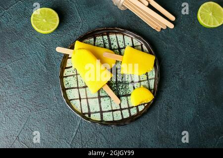 Teller mit leckeren Ananaspopsicles auf dunklem Hintergrund Stockfoto