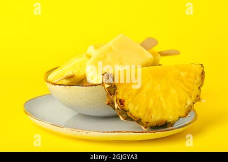 Teller mit leckeren Ananaspopsicles auf farbigem Hintergrund Stockfoto