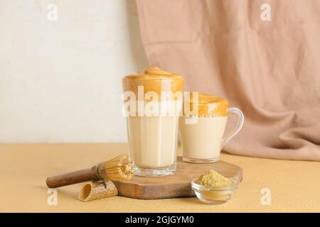 Glas und Tasse schmackhaften dalgona hojicha Latte, Chasen mit Pulver auf dem Tisch Stockfoto