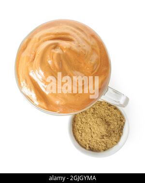 Glastasse mit leckeren dalgona hojicha Latte und Pulver auf weißem Hintergrund Stockfoto