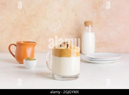 Glas Tasse leckeren dalgona hojicha Latte auf hellem Hintergrund Stockfoto