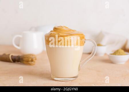 Glas Tasse leckeren dalgona hojicha Latte auf dem Tisch Stockfoto