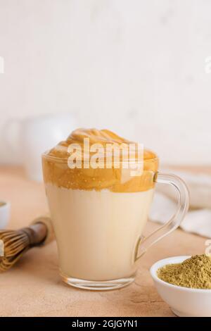 Glastasse von leckeren dalgona hojicha Latte auf farbigem Hintergrund Stockfoto