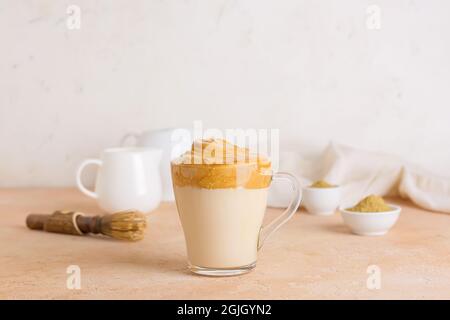 Glas Tasse leckeren dalgona hojicha Latte auf dem Tisch Stockfoto