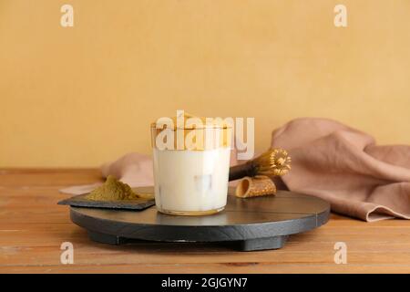 Ein Glas leckeren dalgona hojicha Latte, Chasen und Pulver auf dem Tisch Stockfoto